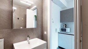 A modern bathroom with a large mirror, a white sink, and a shower area.