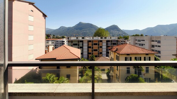 A residential building with a balcony overlooking a mountainous landscape.