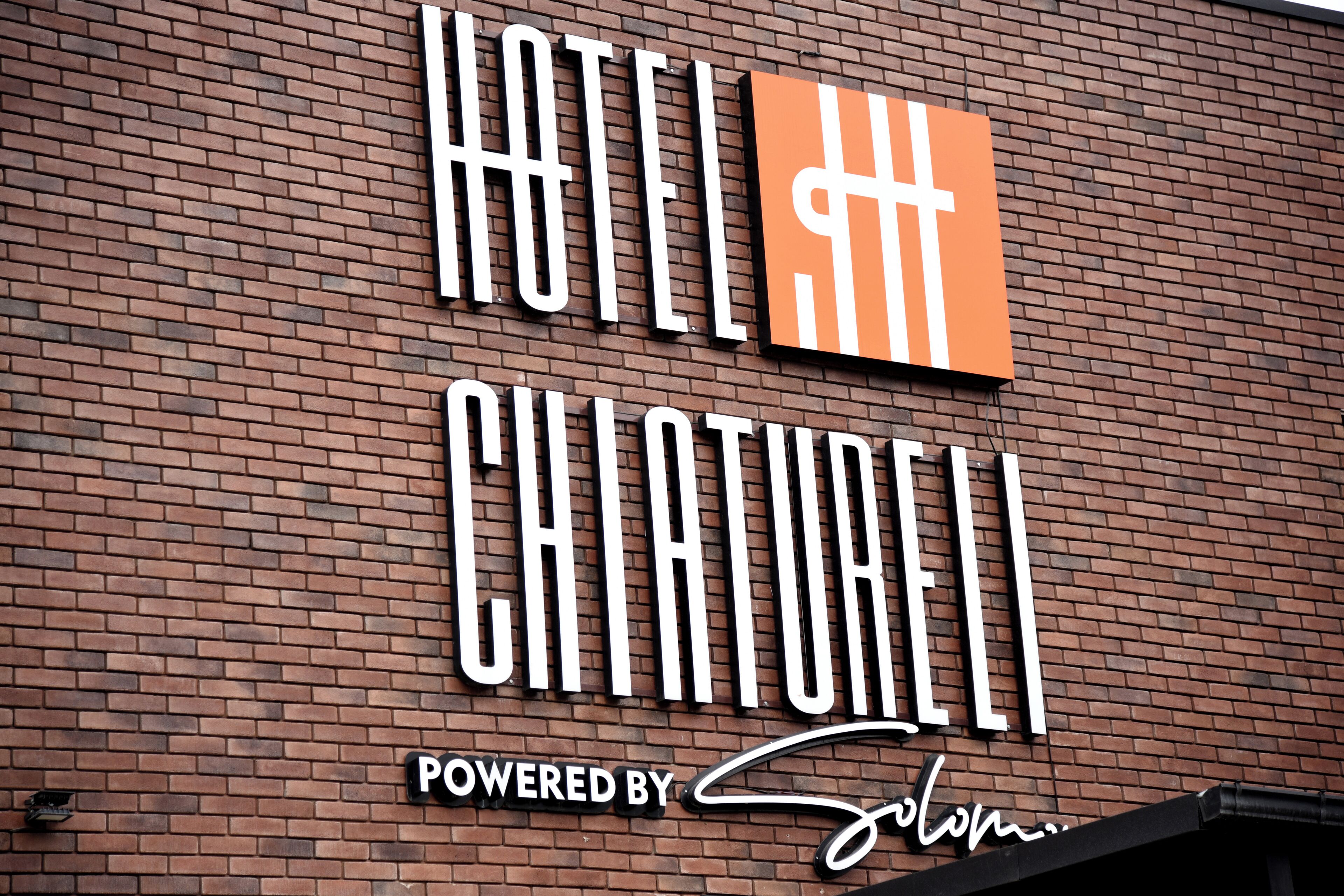 Un cartel de hotel con el nombre 'HOTEL CHIATURRELLI' y un logotipo con una cruz.