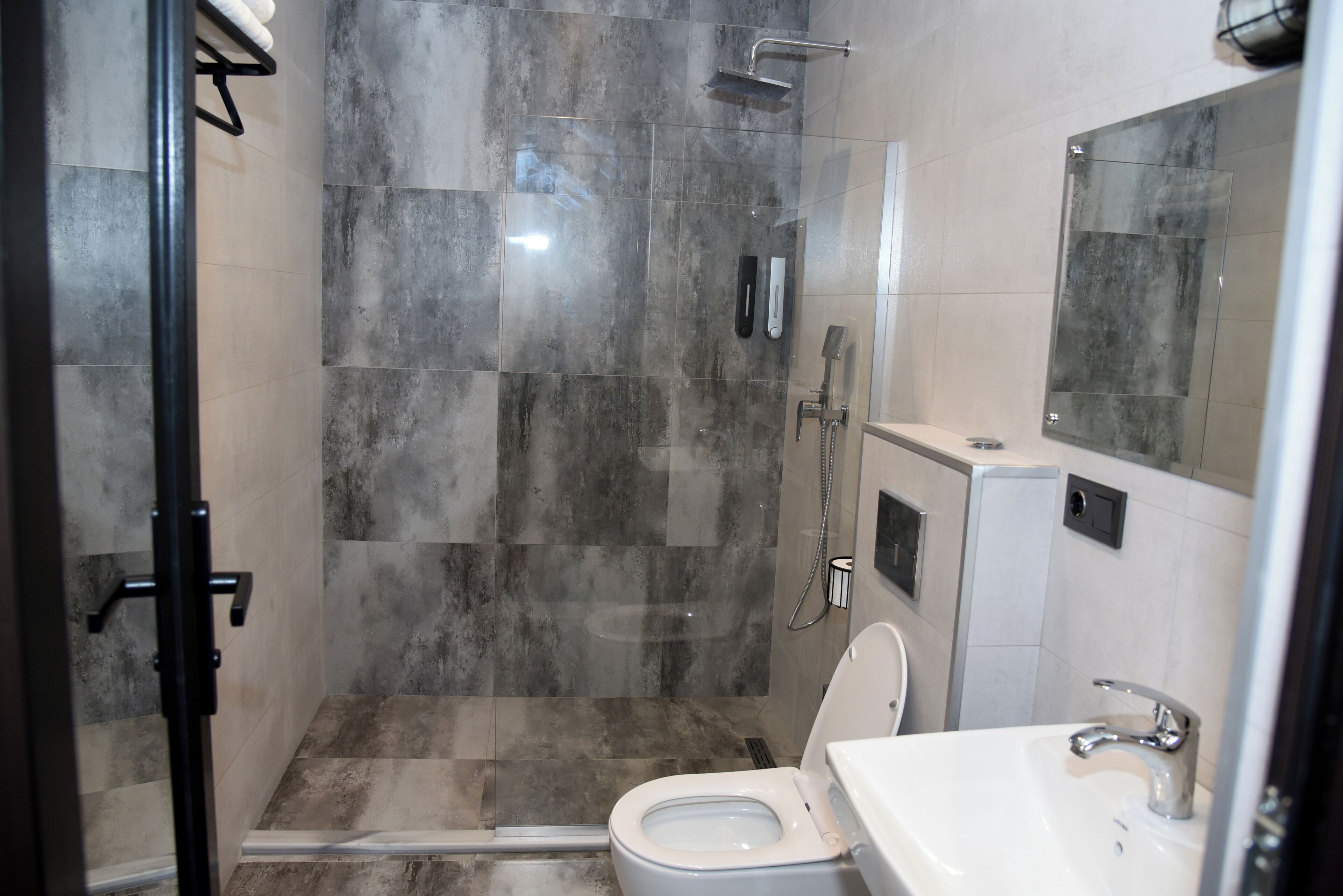 A modern bathroom with a glass-enclosed shower, a white toilet, and a sink with a mirror above it.