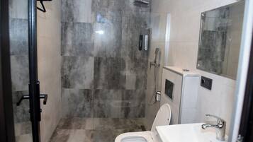 A modern bathroom with a glass-enclosed shower, a white toilet, and a sink with a mirror above it.