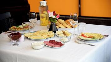 A table set with various dishes, including bread, cheese, and a salad, along with glasses of water and wine.