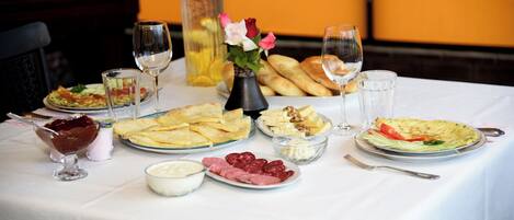 Una mesa servida con diversos platos, incluyendo pan, queso y una ensalada, junto con vasos de agua y vino.