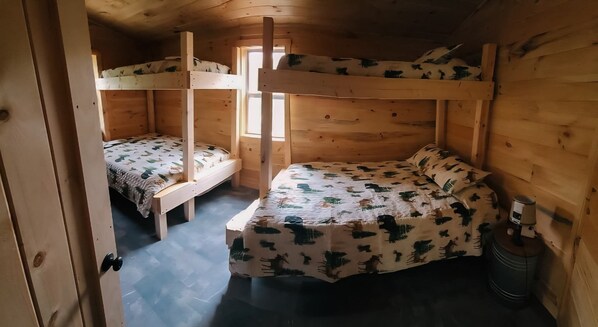 En stuga av trä med två våningssängar, och varje säng har ett mönstrat överkast.