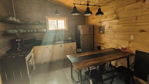 A kitchen with wooden walls, a stove, a refrigerator, and a window. - Charming cabin in Beautiful Patten Maine with WiFi, ATV/Snowmobile trail access (Patten)