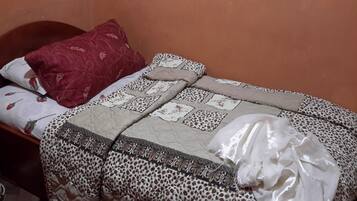 Een bed met een quilt met een patroon en een rode kussen.