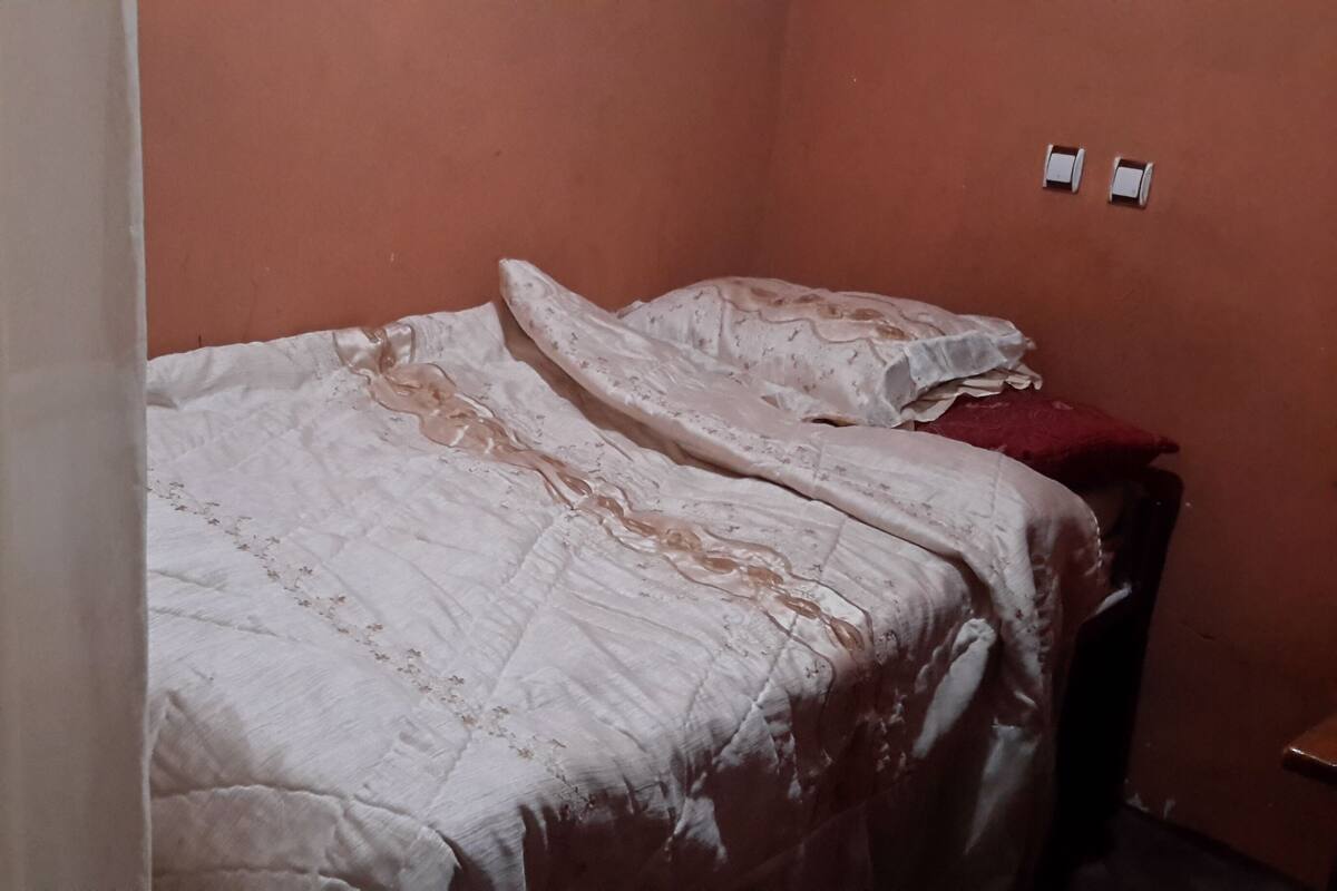 A bedroom with a bed, a nightstand, and a wall socket.