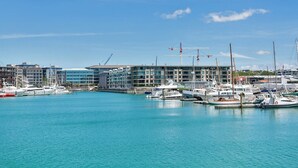 Een jachthaven met aangemeerde boten, moderne gebouwen en een helderblauwe lucht.