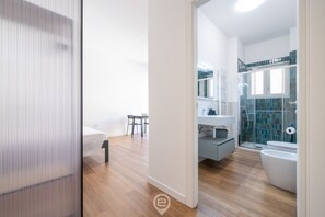 Uma casa de banho moderna com chuveiro, sanita e lavatório.