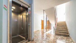 An elevator, a staircase, and a patterned floor.