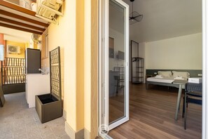 Um espaço de estar compacto com cozinha compacta, área de jantar e quarto com cama e escrivaninha.