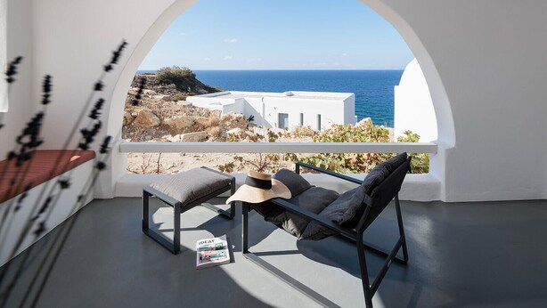 A balcony with a view of the sea, white walls, and a table with a magazine. - Kana Hotel (Naxos)