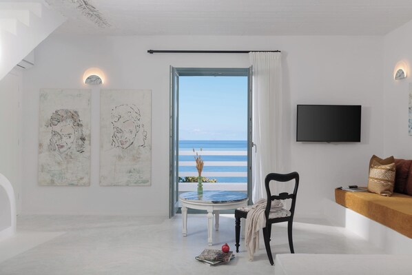 A room with a large window, a flat-screen TV, and two abstract paintings on the wall.