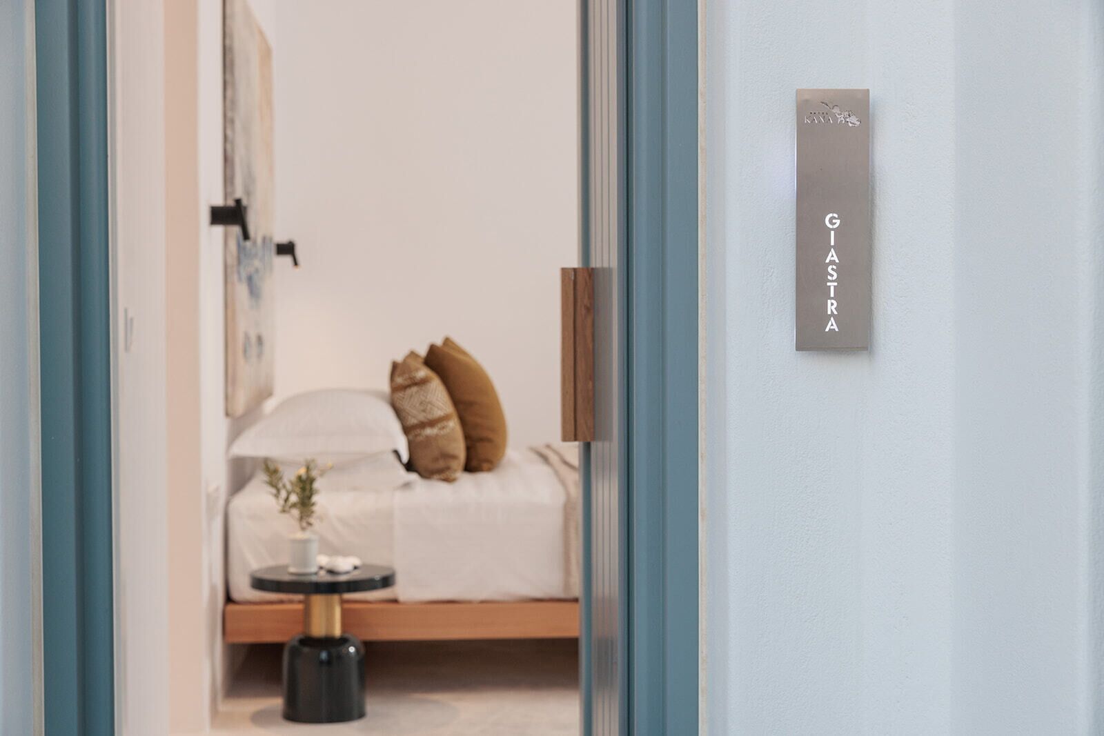 A bedroom with a bed, pillows, a bedside table, and a wall-mounted sign.