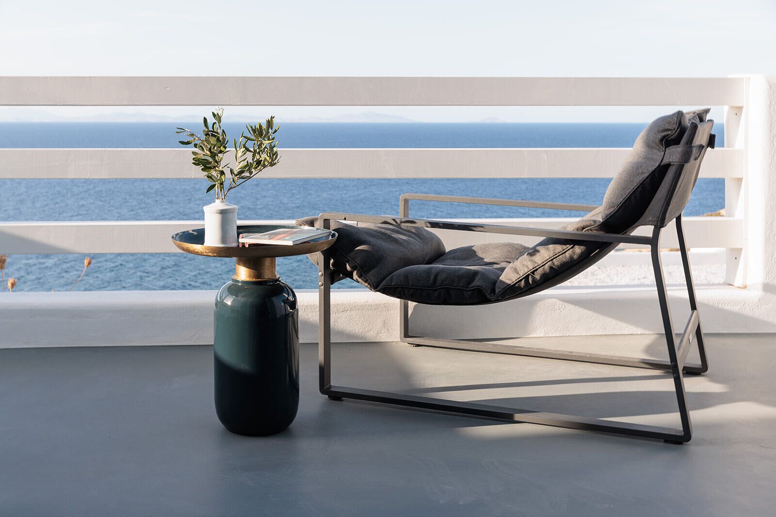 A balcony with a chair and a table, overlooking the sea.