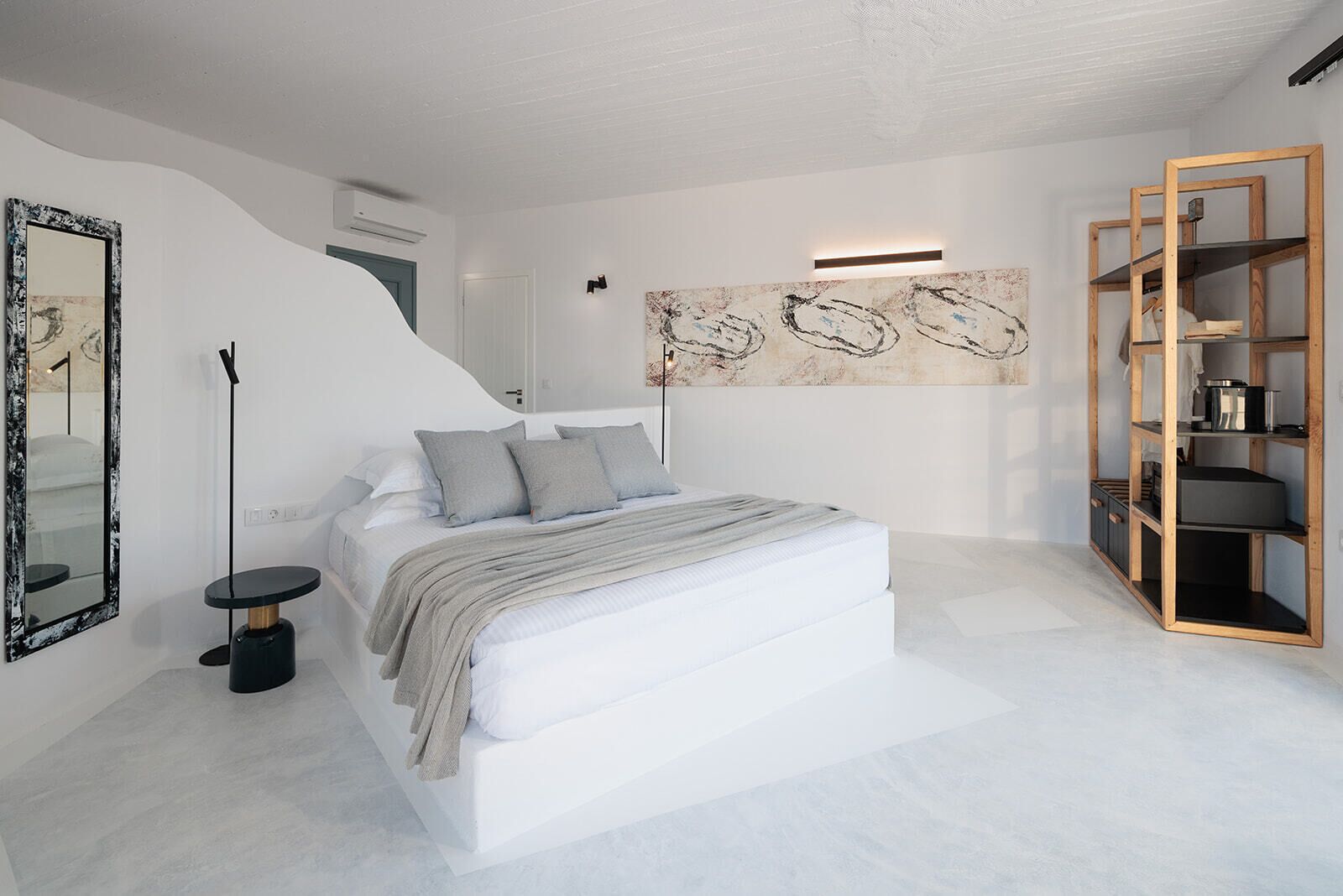 Ein modernes Schlafzimmer mit einem großen Bett, einem Nachttisch, einem Spiegel und einer Holzwandregal.