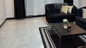 A living room with a black sofa, a coffee table, and a rug.