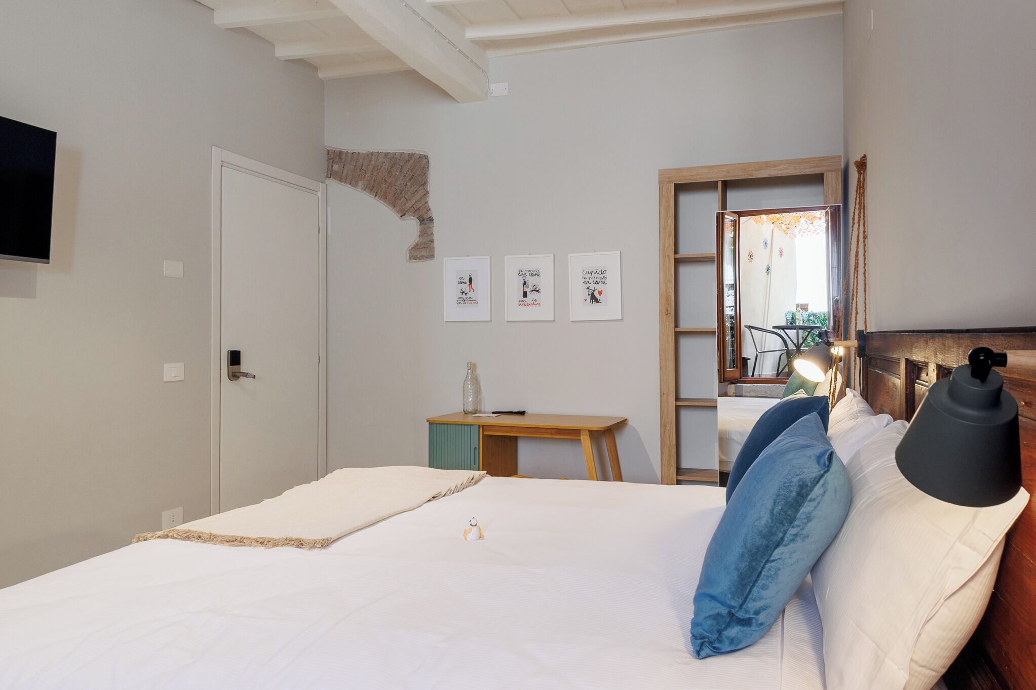 A bedroom with a bed, a desk, and a chair. There are three framed pictures on the wall.