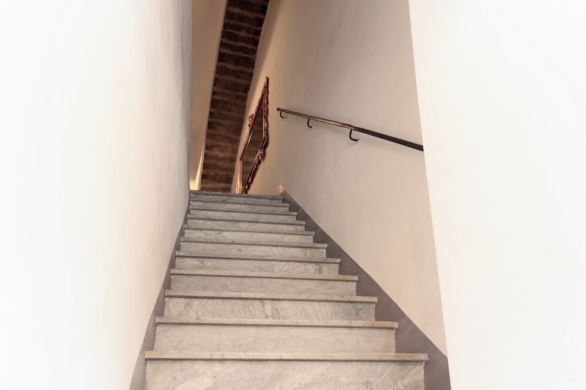 Eine Treppe mit Metallgeländer und einem an der Wand befestigten Ablagefach.