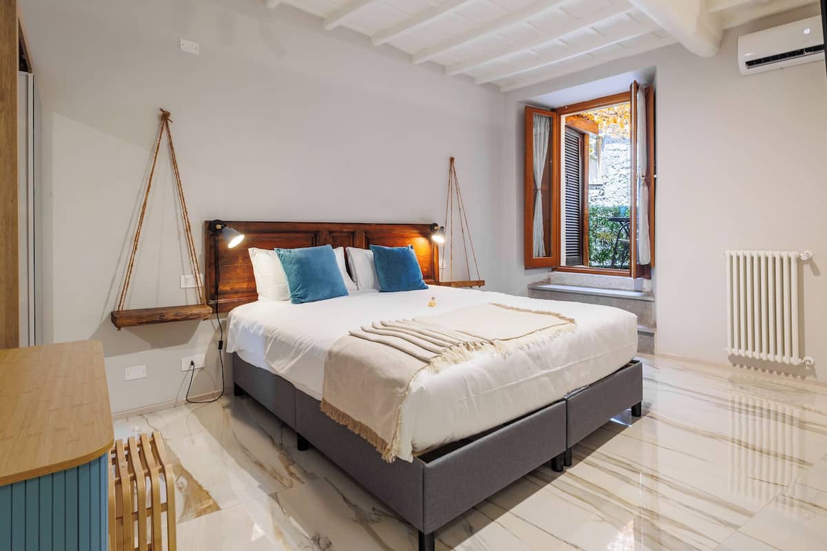 A bedroom with a bed, bedside table, and a window with curtains.