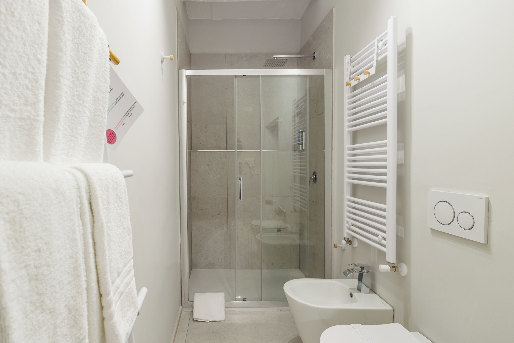 Un baño con ducha de vidrio, un lavabo blanco y un perchero para toallas.