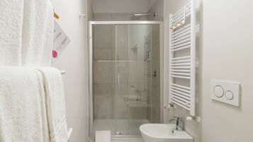 Un baño con ducha de vidrio, un lavabo blanco y un perchero para toallas.
