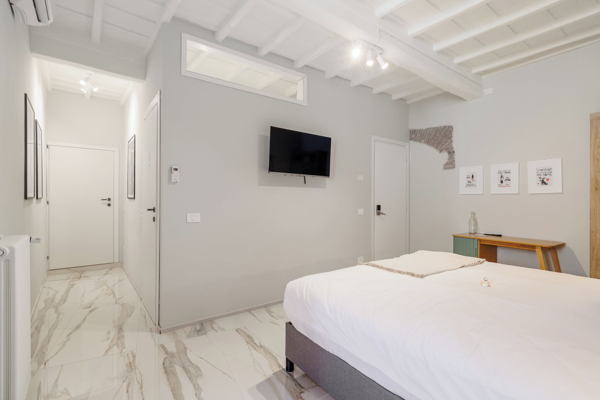 Une chambre à coucher moderne avec un lit, une télévision et une petite table en bois.