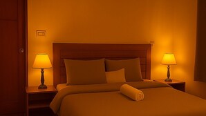 Ein Hotelzimmer mit einem großen Bett, zwei Nachttischlampen, einem Holzkopfteil und einem gemusterten Teppich.