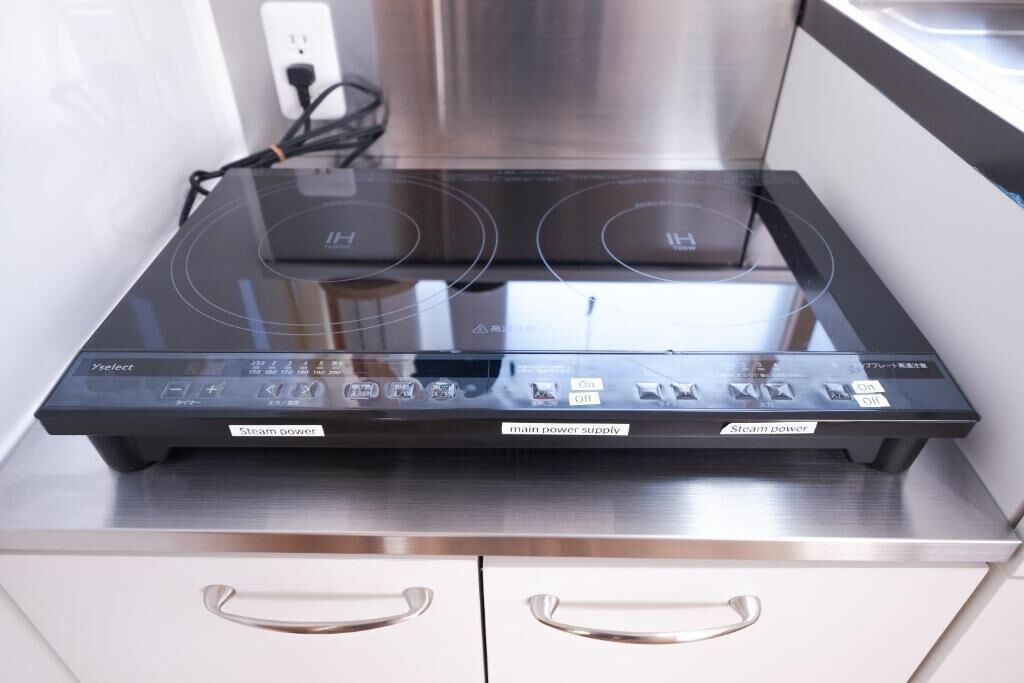 Una cocina con placa de inducción integrada y una campana extractora de acero inoxidable.