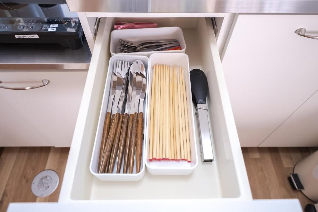 A drawer with utensils neatly organized, including forks, spoons, and chopsticks.