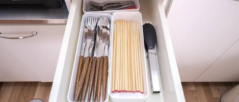 A drawer with utensils neatly organized, including forks, spoons, and chopsticks.