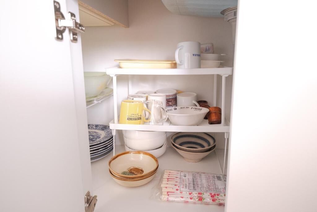 A kitchen with white shelves holding various dishes, a coffee maker, and a yellow mug.