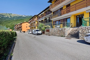 A hotel with multiple balconies, a stone wall, and a mountain view.