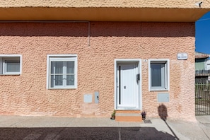 A building with a textured facade, a white door, and two windows.