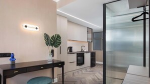 A modern kitchen with a herringbone floor, a dining area with a black table and a teal ottoman, and a sliding glass door leading to a balcony. - Athena Suite by Acropolis Luxury Athens Suites (Athens)