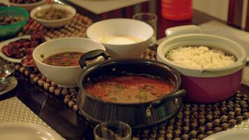 A table with various dishes including a pot of soup, a bowl of rice, and several side dishes.