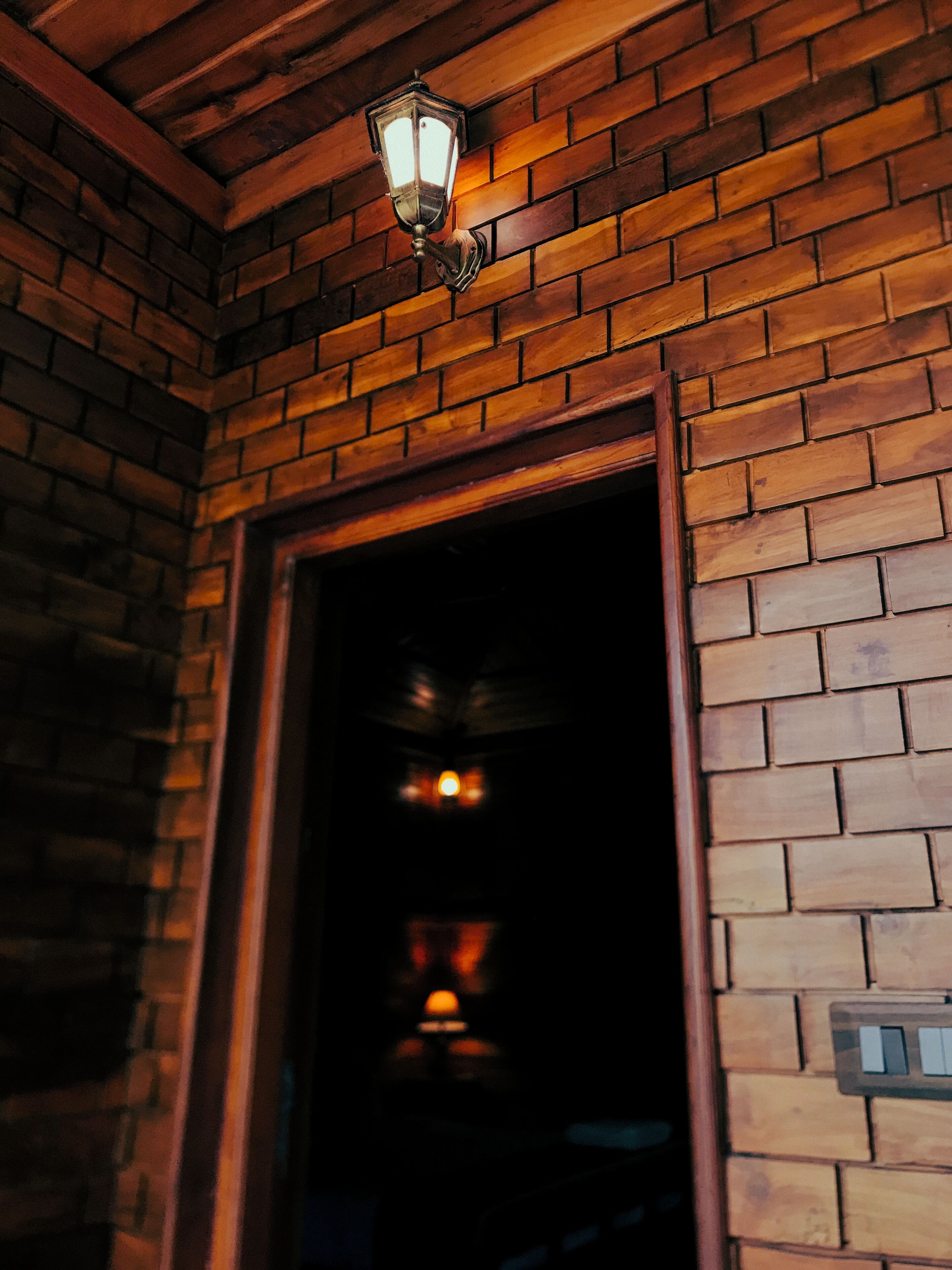 A brick wall with a wooden door frame and a hanging light fixture.