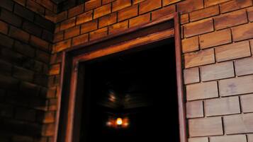 A brick wall with a wooden door frame and a hanging light fixture.