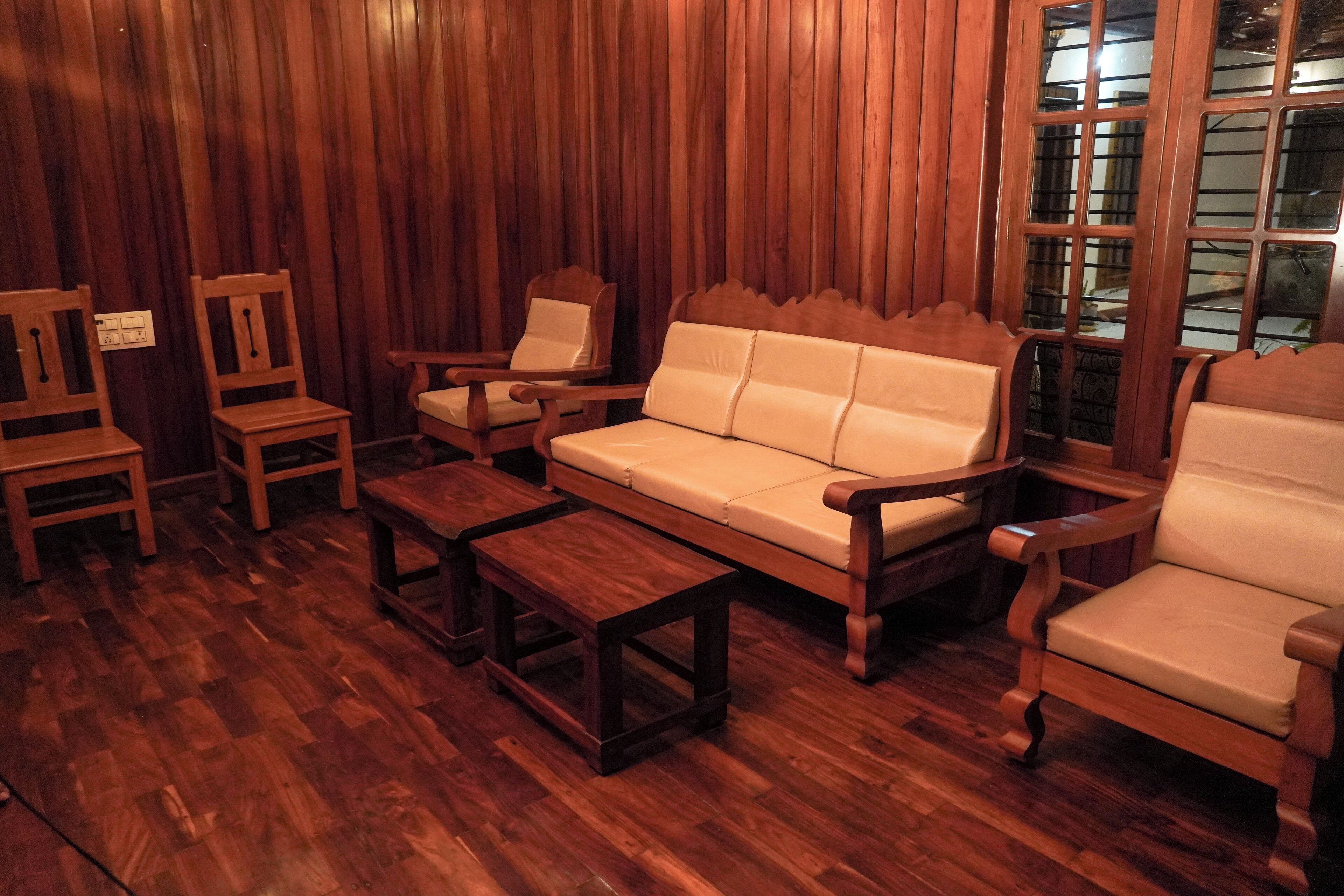 A room with wooden flooring, a sofa, two armchairs, and a small table.