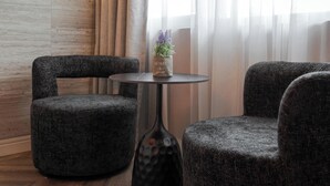 A modern lounge area with two upholstered armchairs, a small round table, and a vase with a plant.