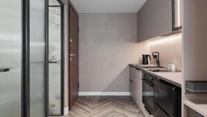 A modern kitchen with a herringbone wood floor, a built-in oven, a stove, and a sink with a kettle.