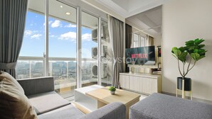 Ein modernes Wohnzimmer mit großem Fenster, Flachbildfernseher und Zimmerpflanze.