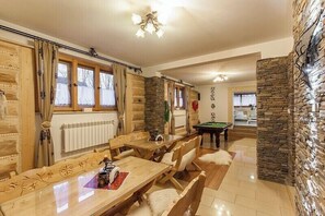 Une pièce chaleureuse avec une table de billard, des meubles en bois, des murs en pierre et une cheminée.