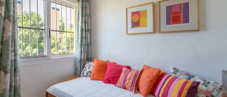 A bedroom with a bed, curtains, and two framed pictures on the wall.