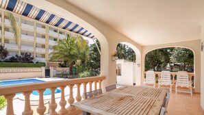A hotel patio with a pool, outdoor seating, and a view of the building's interior.