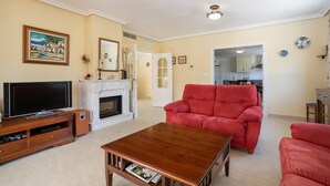 A living room with a television, fireplace, red sofa, and a wooden coffee table.