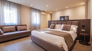 A modern bedroom with a large bed, a sofa, and a small table. - MODENA RELAX Luxury Rent Rooms (Modena)