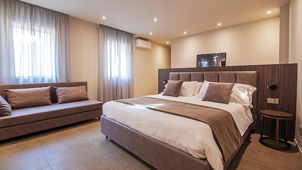 A modern bedroom with a large bed, a sofa, and a small table. - MODENA RELAX Luxury Rent Rooms (Modena)