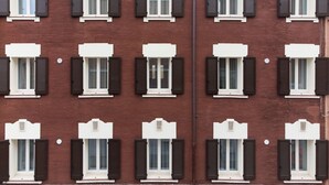 A row of identical apartment buildings with uniform window shutters and white trim. - MODENA RELAX Luxury Rent Rooms (Modena)