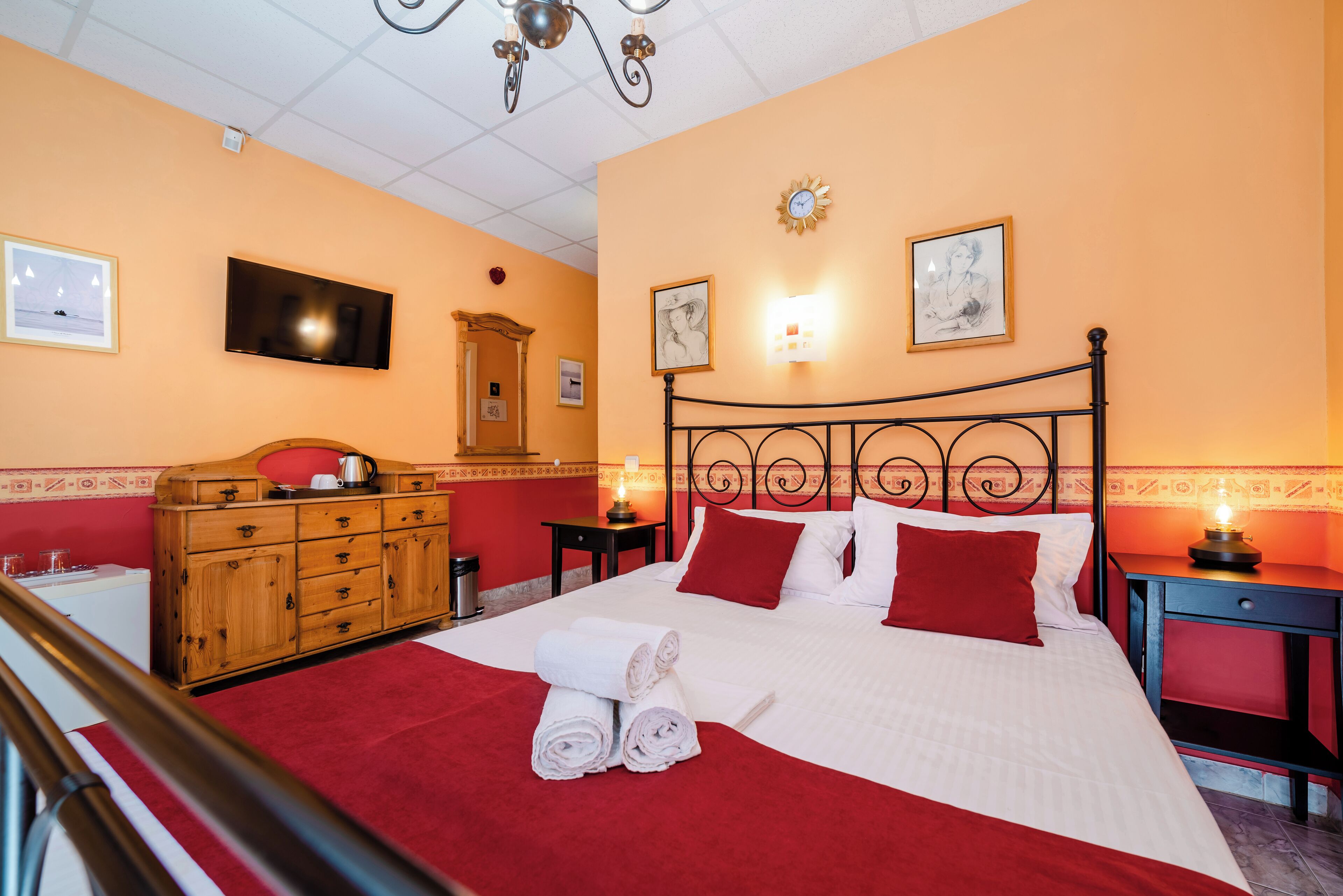 Une chambre d’hôtel avec un lit, une commode en bois et un téléviseur fixé au mur.